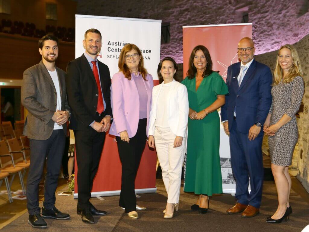 Kambis Kohansal Vajargah, Moritz Ehrmann, Marlies Stubits, Aniko Benkö, Andrea Maller-Weiß, Martin Geiger, and Eva Huber stehen nebeneinander vor zwei Roll-Up-Bannern. Alle sind geschäftlich gekleidet. Die Gruppe befindet sich in einem Saal mit Steinwänden und leeren Stuhlreihen im Hintergrund. Die Atmosphäre wirkt professionell und freundlich.Foto: LEXI