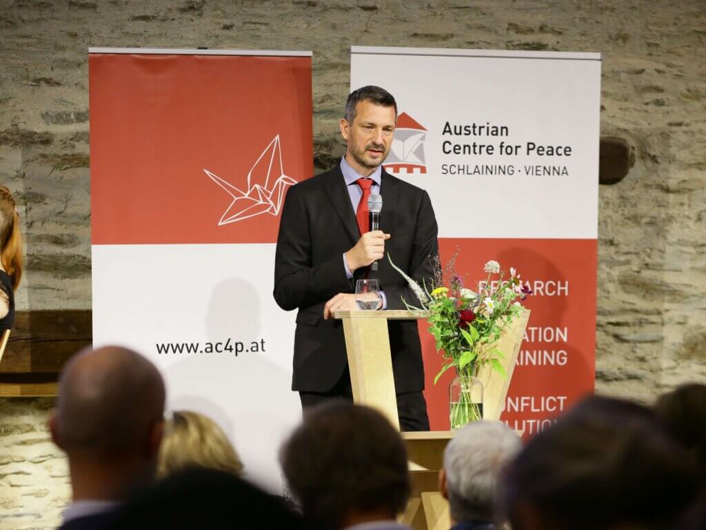 Es sieht so aus, als ob du ein Foto vom 2. Österreichischen Friedensforum auf Burg Schlaining geteilt hast, auf dem Moritz Ehrmann, der Direktor des Austrian Centre for Peace, seine Begrüßungsworte hält. Foto: Lexi