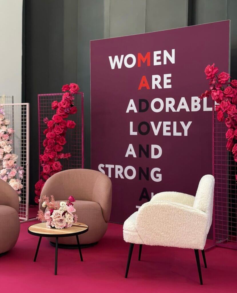 Gemütliche Lounge-Ecke mit inspirierender Botschaft für Frauen auf modernem Hintergrund und Blumenakzenten.